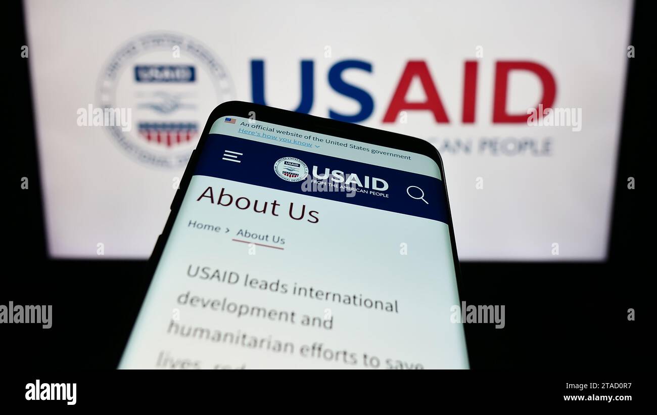 Smartphone con sito Web dell'Agenzia degli Stati Uniti per lo sviluppo internazionale (USAID) davanti al logo. Mettere a fuoco in alto a sinistra sul display del telefono. Foto Stock