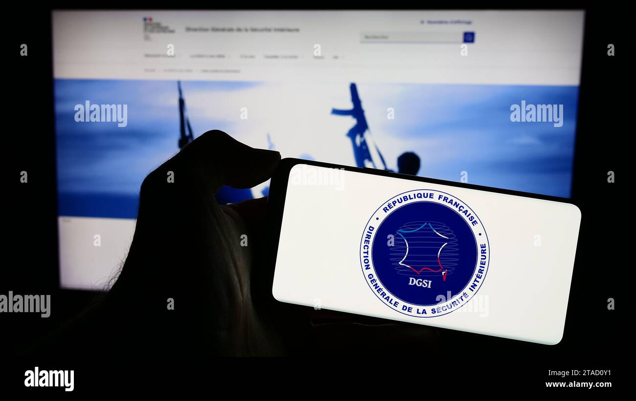 Persona che possiede il cellulare con il logo della Direction Générale de la Sécurité Intérieure (DGSI) davanti alla pagina web. Concentrarsi sul display del telefono. Foto Stock