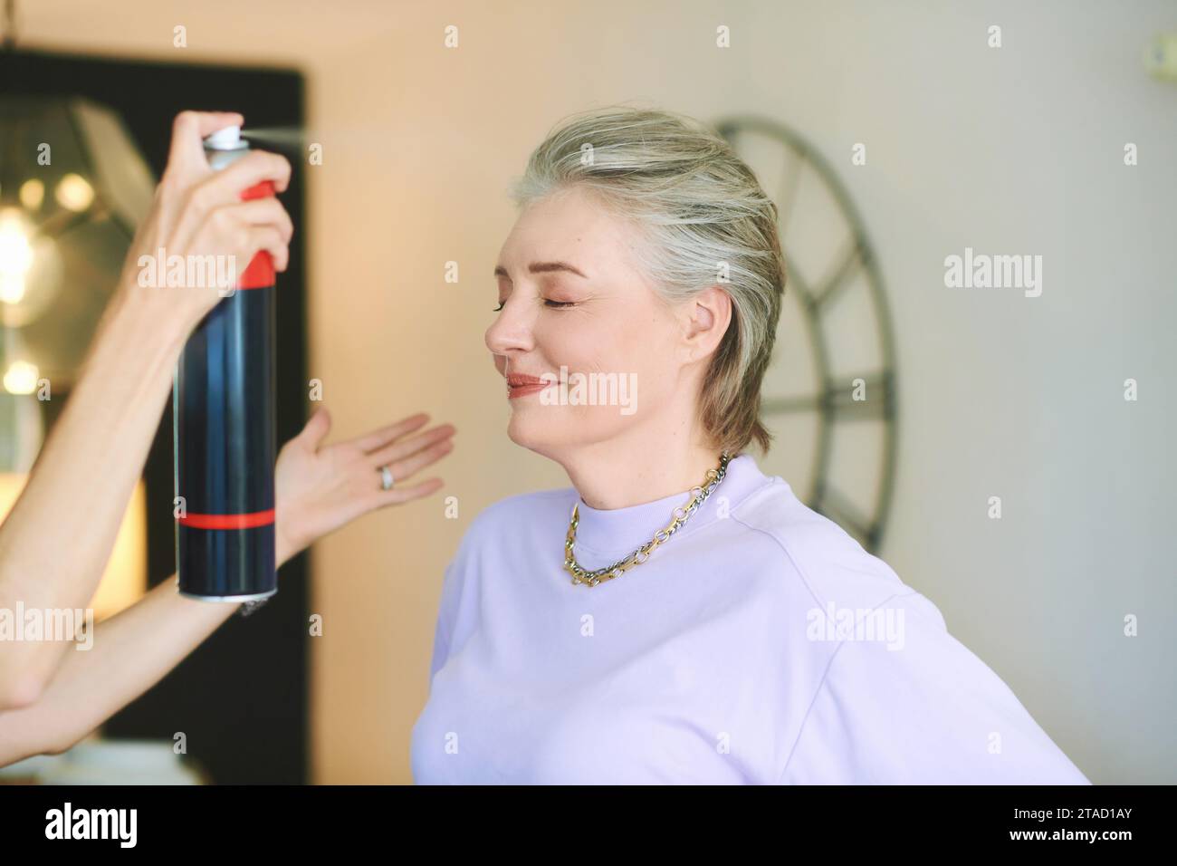 Ritratto di una donna di mezza età al parrucchiere, nuovo trattamento di capelli con spray per capelli Foto Stock