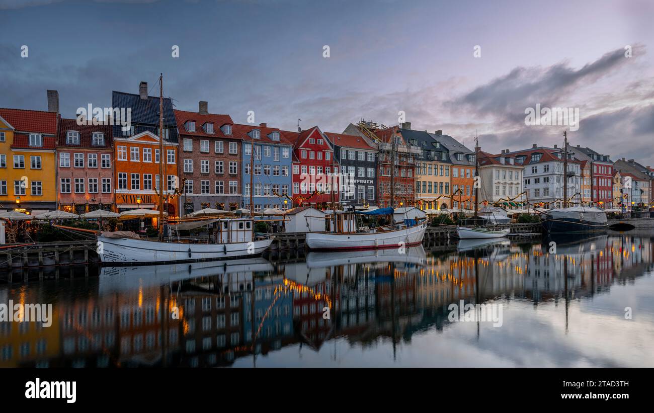 Barche da pesca e decorazioni natalizie lungo il canale di Nyhamns che si riflettono nell'acqua morta, Copenhagen, 25 novembre 2023 Foto Stock