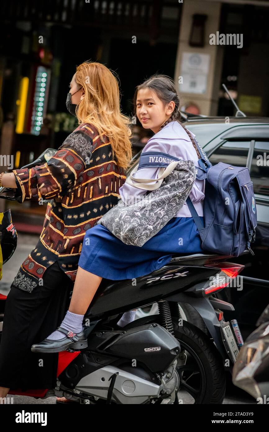 Una studentessa tailandese si siede sul retro di un taxi in moto che viaggia attraverso le strade trafficate di Pattaya, Bangkok. Foto Stock