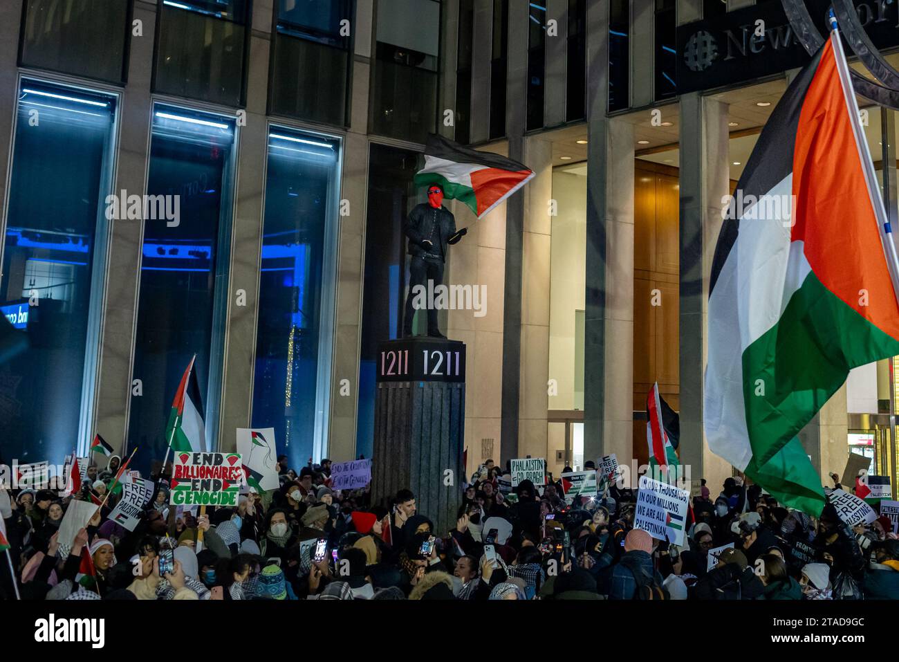 NEW YORK, NEW YORK - NOVEMBRE 29: Un sostenitore pro-palestinese ha una bandiera palestinese scalata in cima a una stazione di indirizzo durante una manifestazione presso l'edificio News Corp. Vicino all'illuminazione dell'albero Rockefeller il 29 novembre 2023 a New York City. Il raduno arriva quando la tregua iniziale di quattro giorni tra Israele e Hamas è stata prolungata di due giorni mettendo in pausa le sette settimane di guerra che ha ucciso migliaia di persone a Gaza a seguito dell'attacco di Hamas del 7 ottobre in Israele. (Foto di Michael Nigro/Sipa USA) Foto Stock