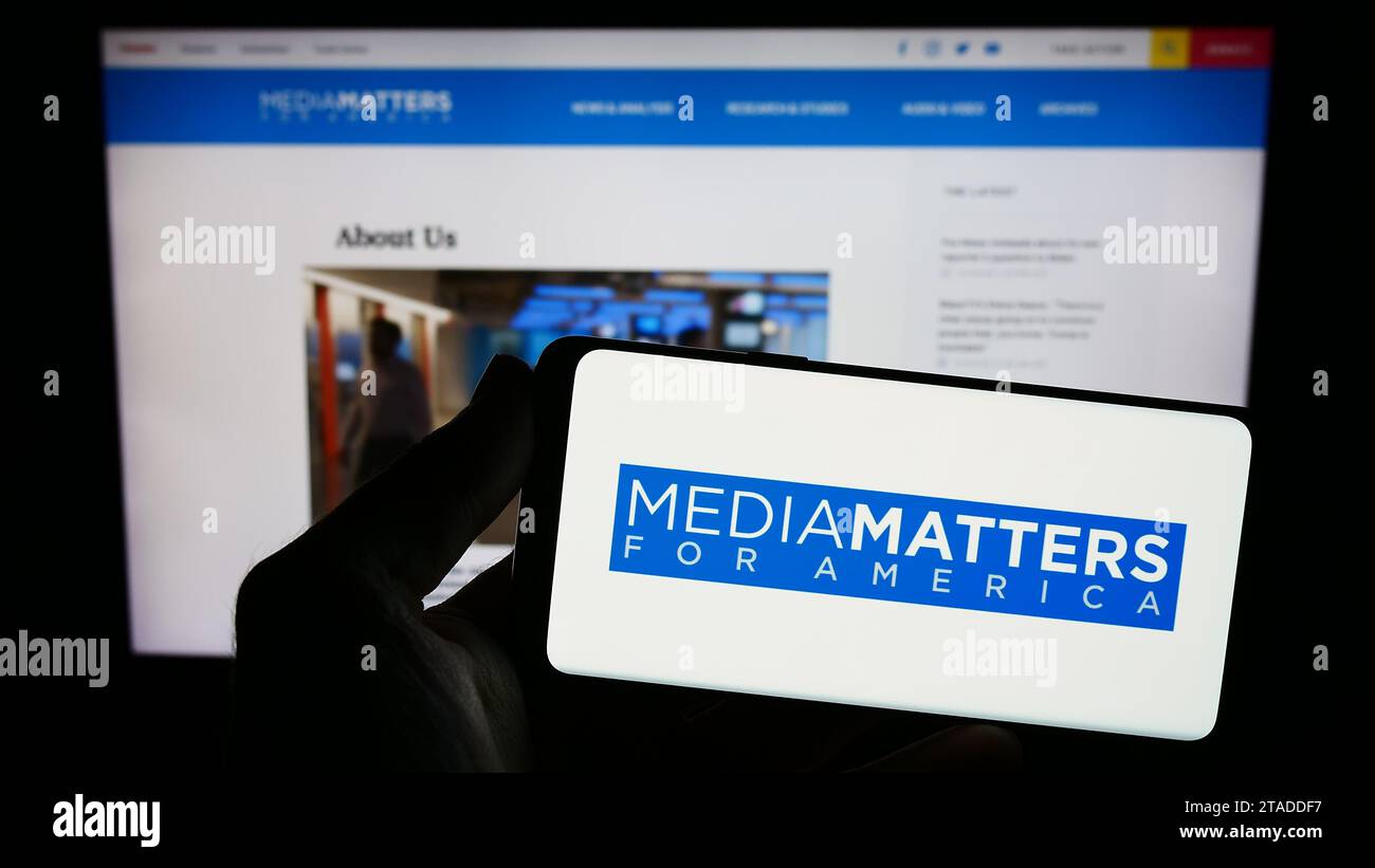 Persona che possiede uno smartphone con il logo del gruppo di sorveglianza statunitense Media Matters for America (MMfA) davanti al sito Web. Concentrarsi sul display del telefono. Foto Stock