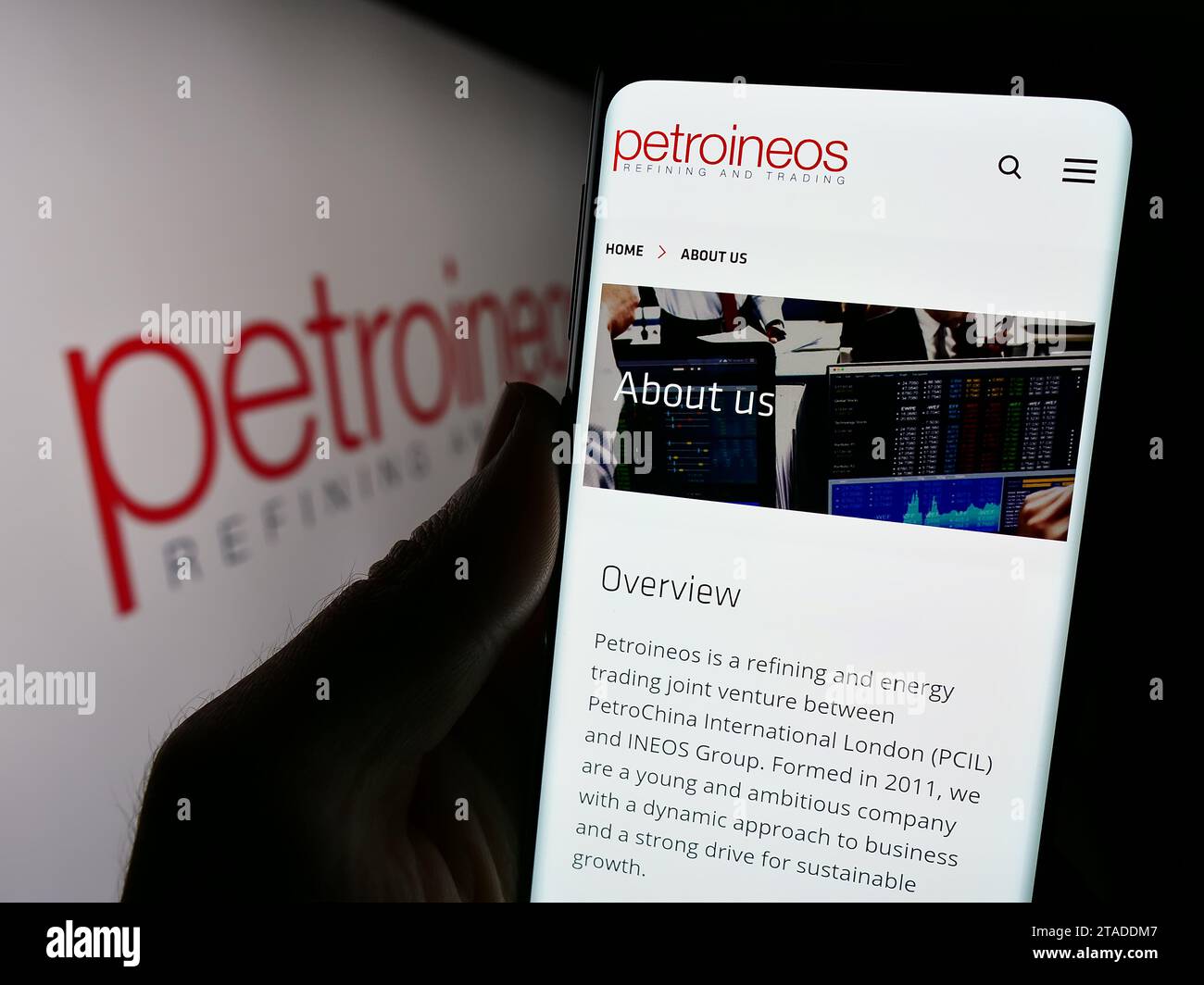 Persona in possesso di cellulare con pagina web della compagnia petrolifera britannica PetroIneos Trading Limited con logo. Concentrarsi sul centro del display del telefono. Foto Stock