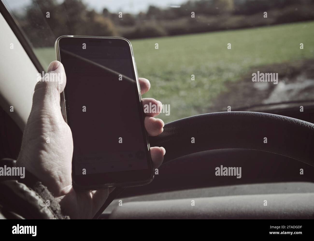mano che tiene un telefono mentre si guida un'auto Foto Stock