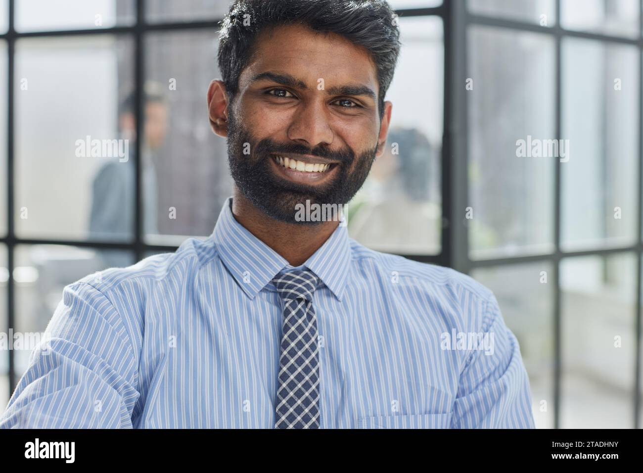 la barba di un investitore maschile che guarda la fotocamera e sorride in un ufficio moderno Foto Stock