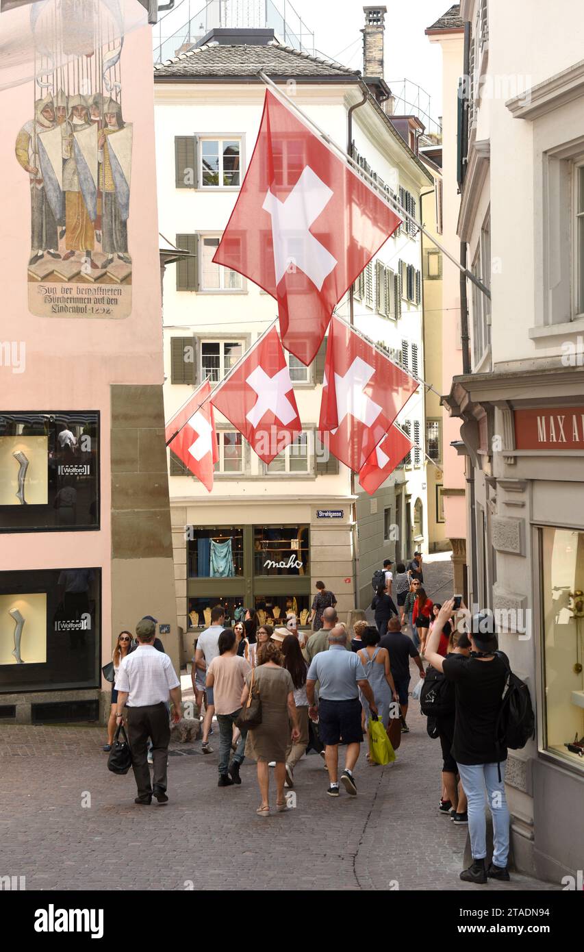 Zurigo, Svizzera - 3 giugno 2017: Persone per la strada di Zurigo decorate con bandiere della Svizzera. Bandiere svizzere sulla facciata dell'edificio a histori Foto Stock