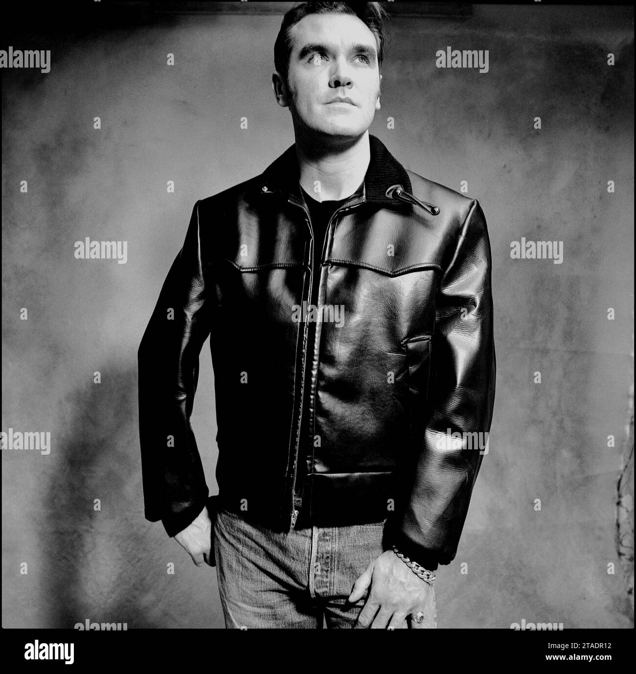 Potente ritratto a metà foto in bianco e nero della leggendaria rockstar, cantautore Morrissey in giacca di pelle e jeans blu per promuovere il suo singolo "Sunny" nel 1995 per Parlophone Records. Foto Stock