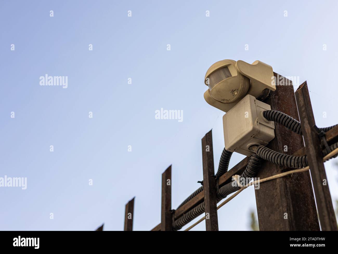 Videosorveglianza stradale e sistema di sicurezza. Piccola telecamera montata su una recinzione metallica contro un cielo blu Foto Stock