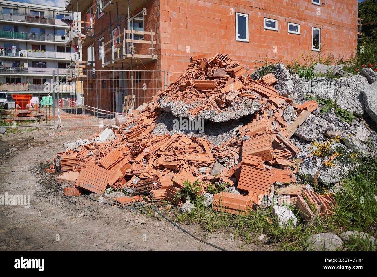 Cumulo di detriti edili - pezzi rotti di mattoni e blocchi di cemento, nuovo edificio costruito sullo sfondo Foto Stock