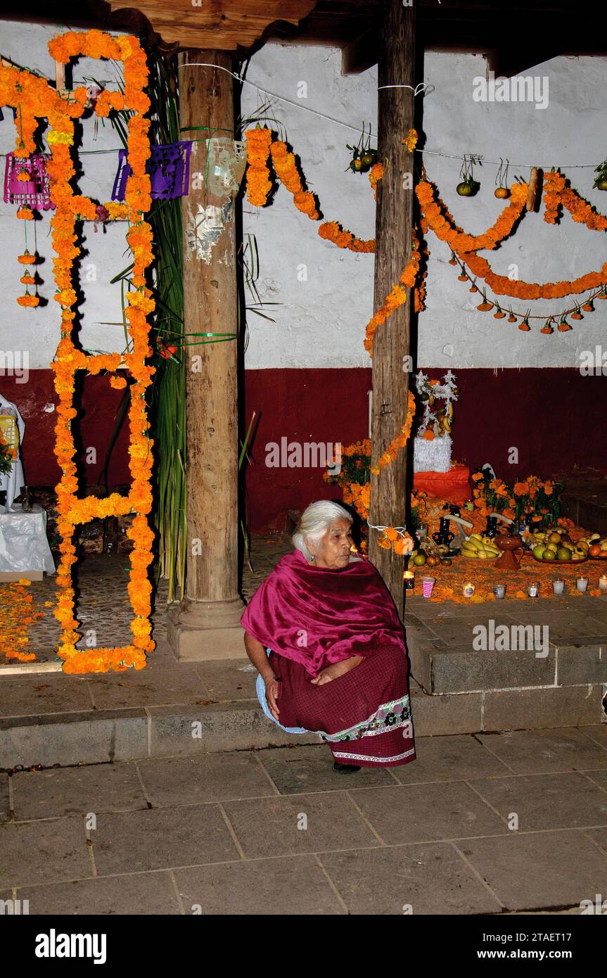 Santa Fe de la Laguna, Michoacan, Messico - 1° novembre 2023. Una donna in luminoso vestito tradizionale indiano è seduta fuori il giorno della morte in Messico Foto Stock