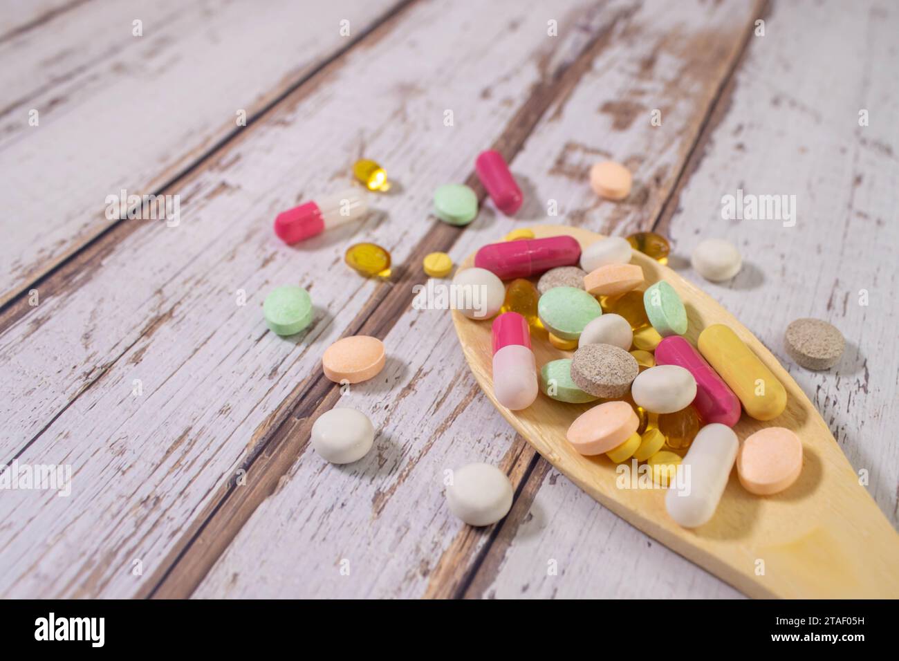 Pillole medicinali miste, compresse su cucchiaio di legno su sfondo blu. Molte pillole diverse con spazio per il testo. Assistenza sanitaria. Vista dall'alto. Copia spazio. Nuovo ima Foto Stock