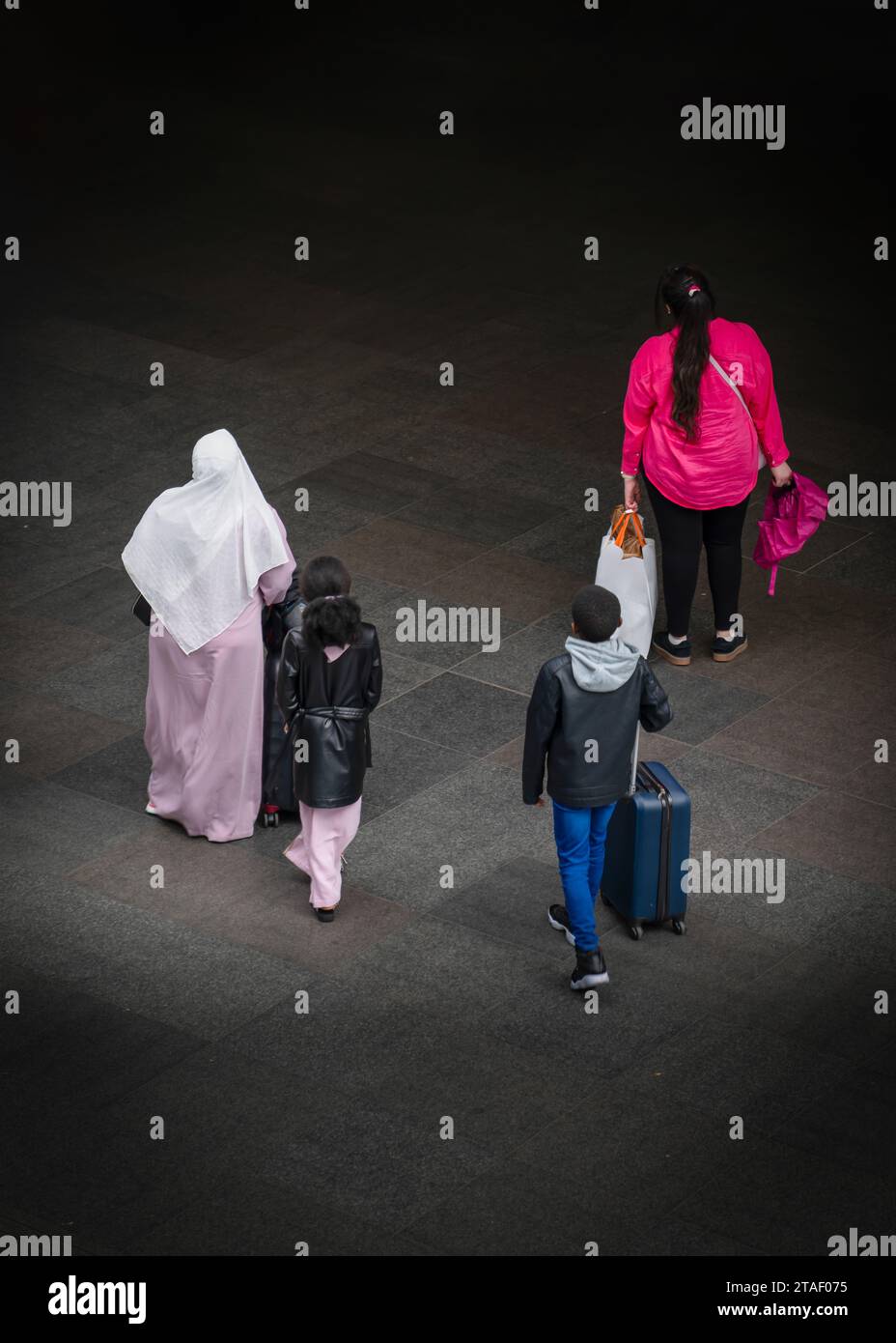 Vista posteriore di una famiglia mediorientale che viaggia con i propri bagagli Foto Stock