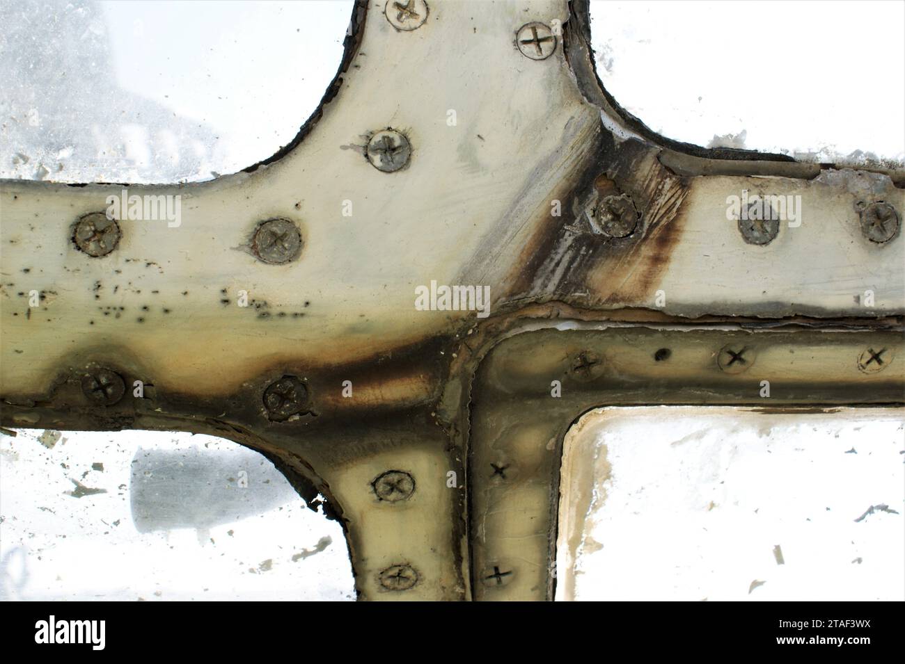 Telaio della finestra rugginito di un vecchio aereo con viti. Foto Stock