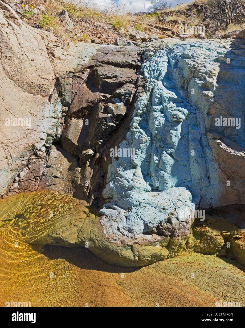 I depositi di rame ricoprono la superficie rocciosa di una piccola cascata. Foto Stock