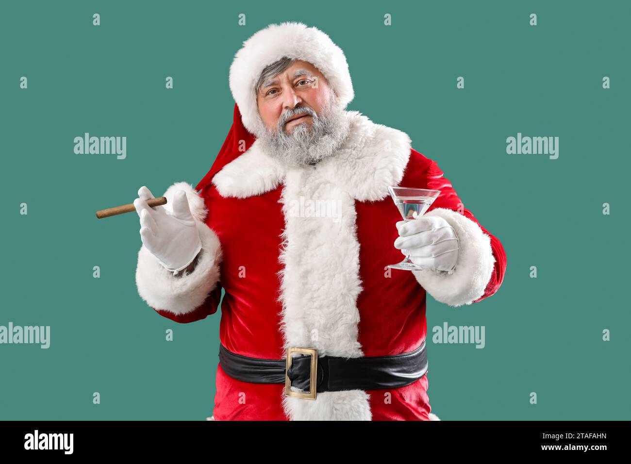 Babbo Natale cattivo con sigaro e cocktail su sfondo verde Foto Stock