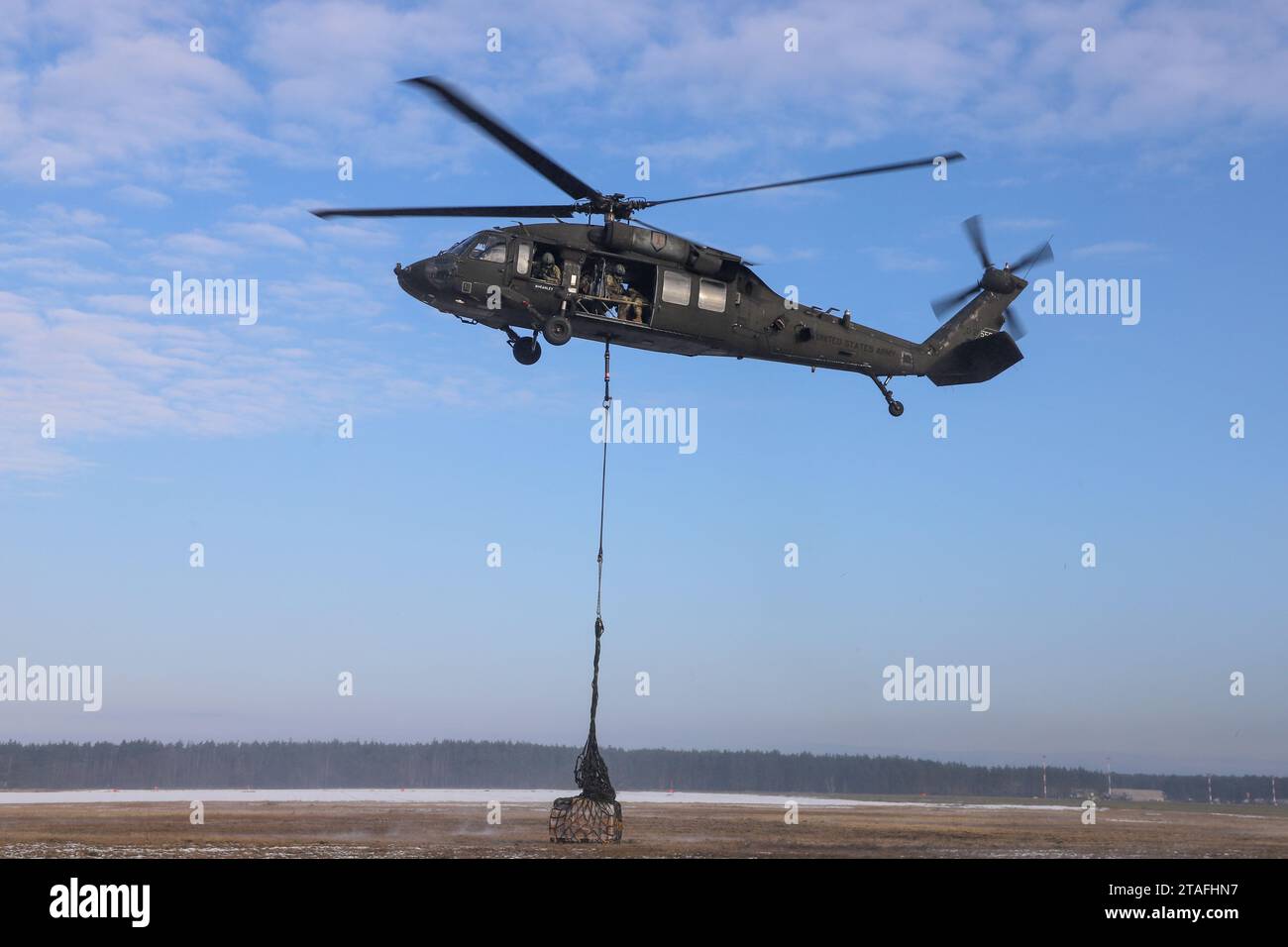 Soldati dell'esercito statunitense assegnati alla Alpha Company, 129th Division Sustainment Support Battalion, parte della 3rd Division Sustainment Brigade 's Taskforce Provider, e aviatori assegnati alla 1st Combat Aviation Brigade, esercitano ad agganciare un carico di imbracatura a un elicottero UH-60 Black Hawk, a Powidz, Polonia, il 30 novembre 2023. La 3rd Division Sustainment Brigade, che guida una forza multicompositiva di unità di sostegno, fornisce forze pronte e postulate, combattenti credibili e una presenza avanzata in Europa, consentendo una risposta rapida alla crisi e una deterrenza agli avversari. (Foto dell'esercito degli Stati Uniti di SPC. Elsi Delgad Foto Stock
