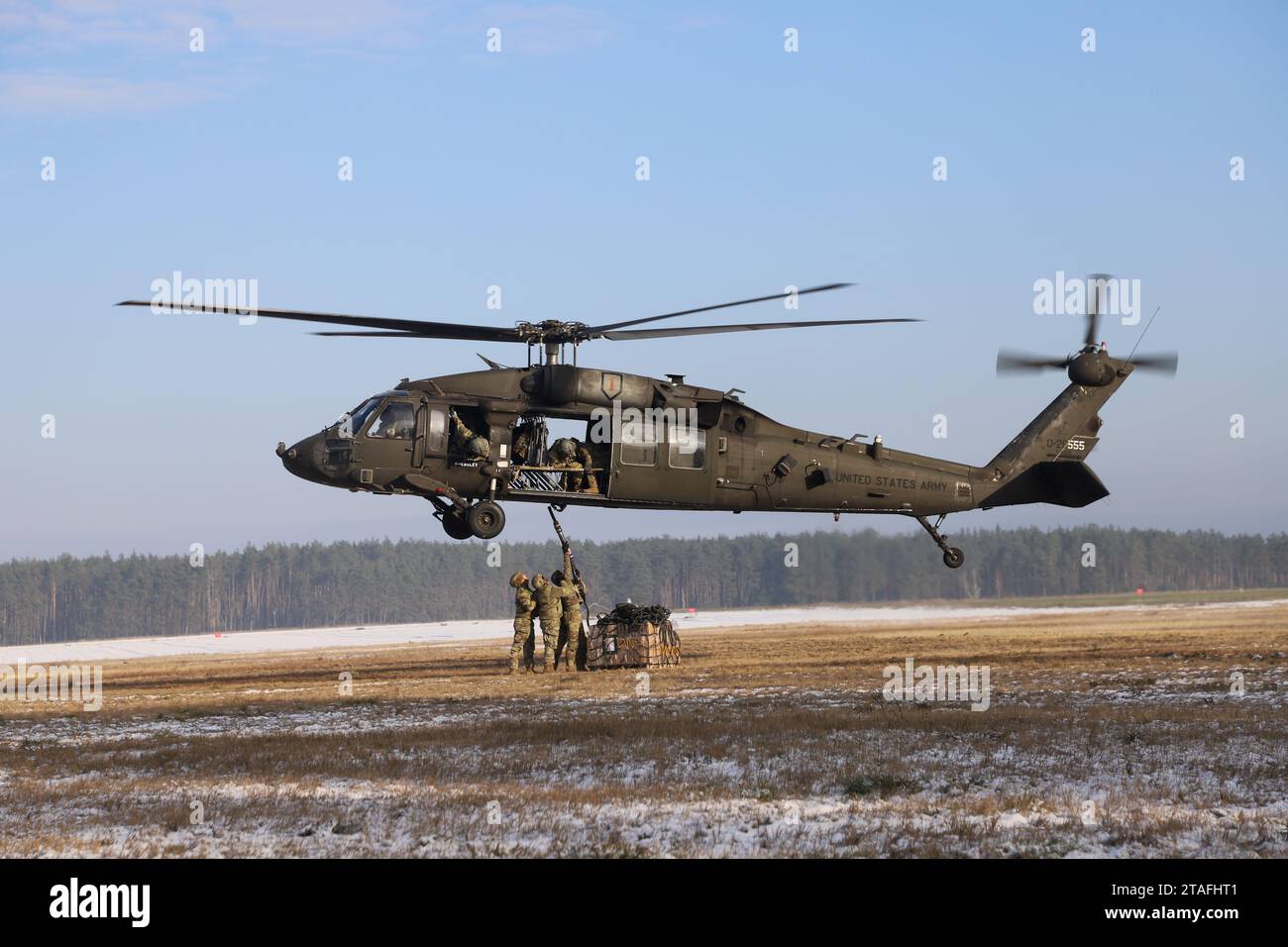Soldati dell'esercito statunitense assegnati alla Alpha Company, 129th Division Sustainment Support Battalion, parte della 3rd Division Sustainment Brigade 's Taskforce Provider, e aviatori assegnati alla 1st Combat Aviation Brigade, esercitano ad agganciare un carico di imbracatura a un elicottero UH-60 Black Hawk, a Powidz, Polonia, il 30 novembre 2023. La 3rd Division Sustainment Brigade, che guida una forza multicompositiva di unità di sostegno, fornisce forze pronte e postulate, combattenti credibili e una presenza avanzata in Europa, consentendo una risposta rapida alla crisi e una deterrenza agli avversari. (Foto dell'esercito degli Stati Uniti di SPC. Elsi Delgad Foto Stock