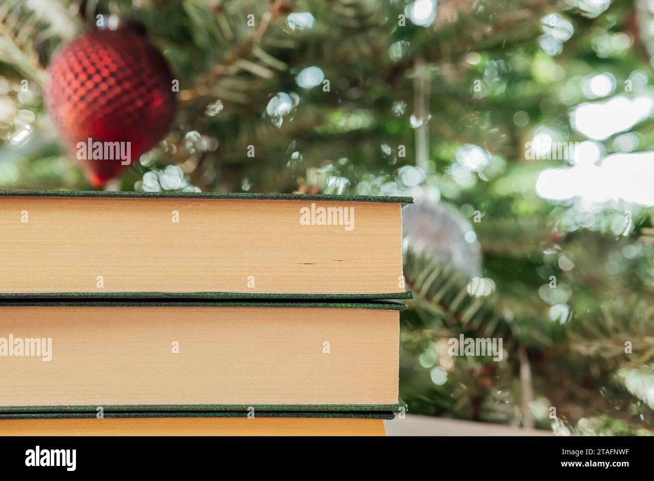 Libri di Natale e Capodanno. I libri con copertine verdi sono impilati sullo sfondo dell'albero di Natale.atmosfera accogliente. Libri per la stagione invernale. Libri su Natale e inverno Foto Stock