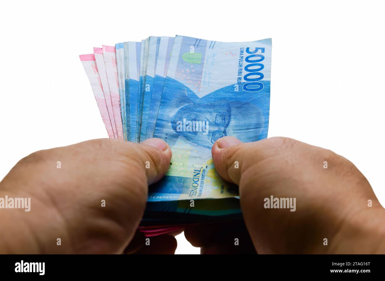 La Rupia indonesiana IDR è la valuta ufficiale dell'Indonesia. Mano di un uomo asiatico che tiene un po' di soldi per pagare. Concetto economico Business di investimento Foto Stock