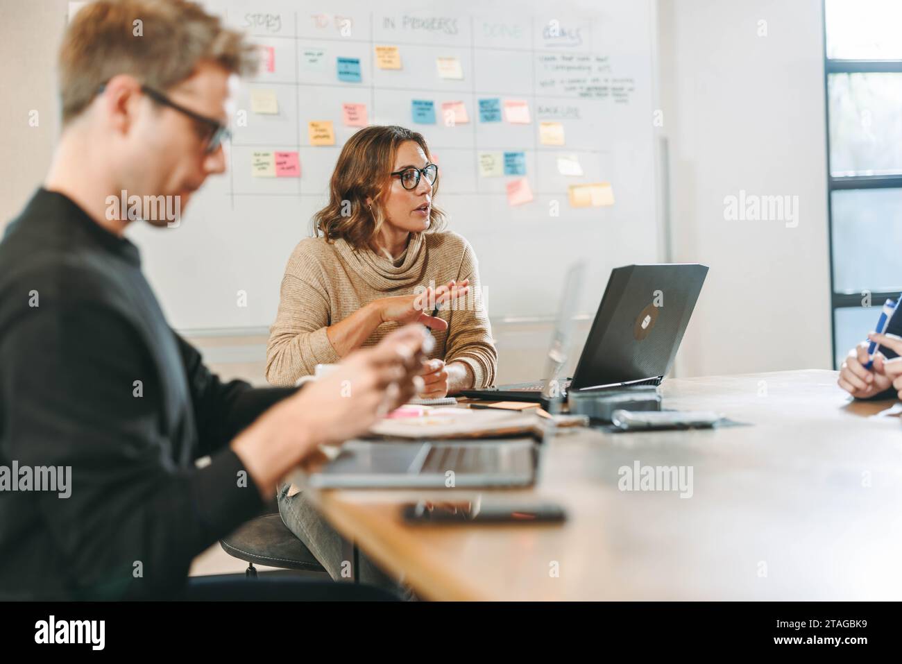 I professionisti si impegnano in una discussione dinamica e collaborativa in una riunione del Consiglio di amministrazione. Si scambiano idee creative e utilizzano la tecnologia Foto Stock