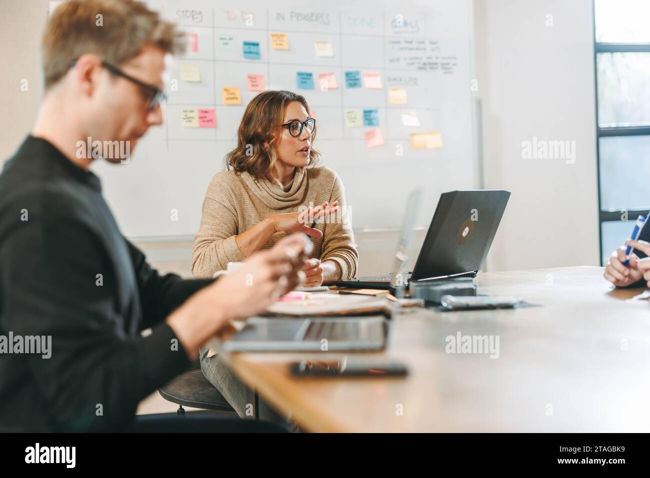 I professionisti si impegnano in una discussione dinamica e collaborativa in una riunione del Consiglio di amministrazione. Si scambiano idee creative e utilizzano la tecnologia Foto Stock