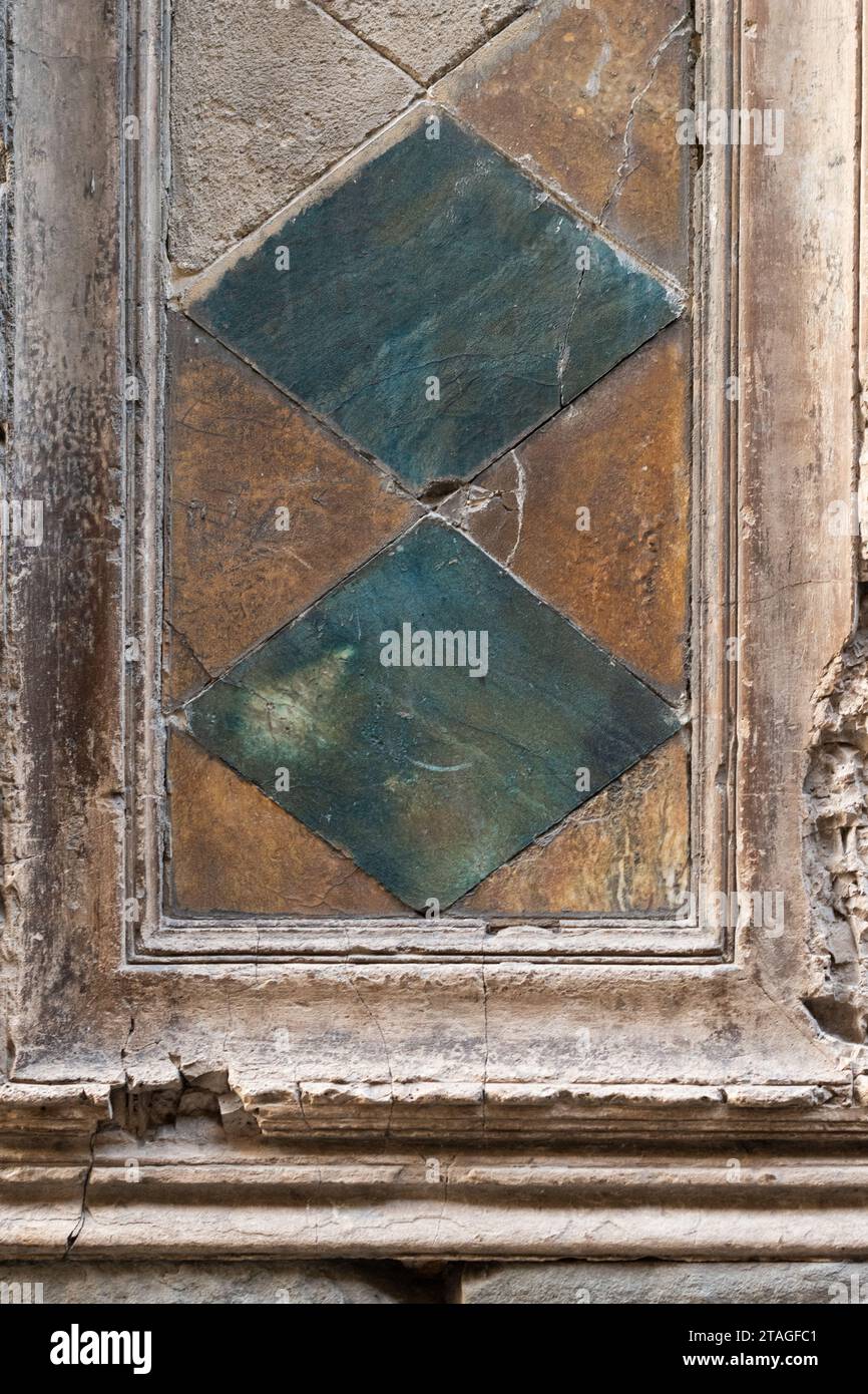 Due diamanti verdi e blu sono allestiti in una sezione di una vecchia porta malandata in Toscana, Italia Foto Stock