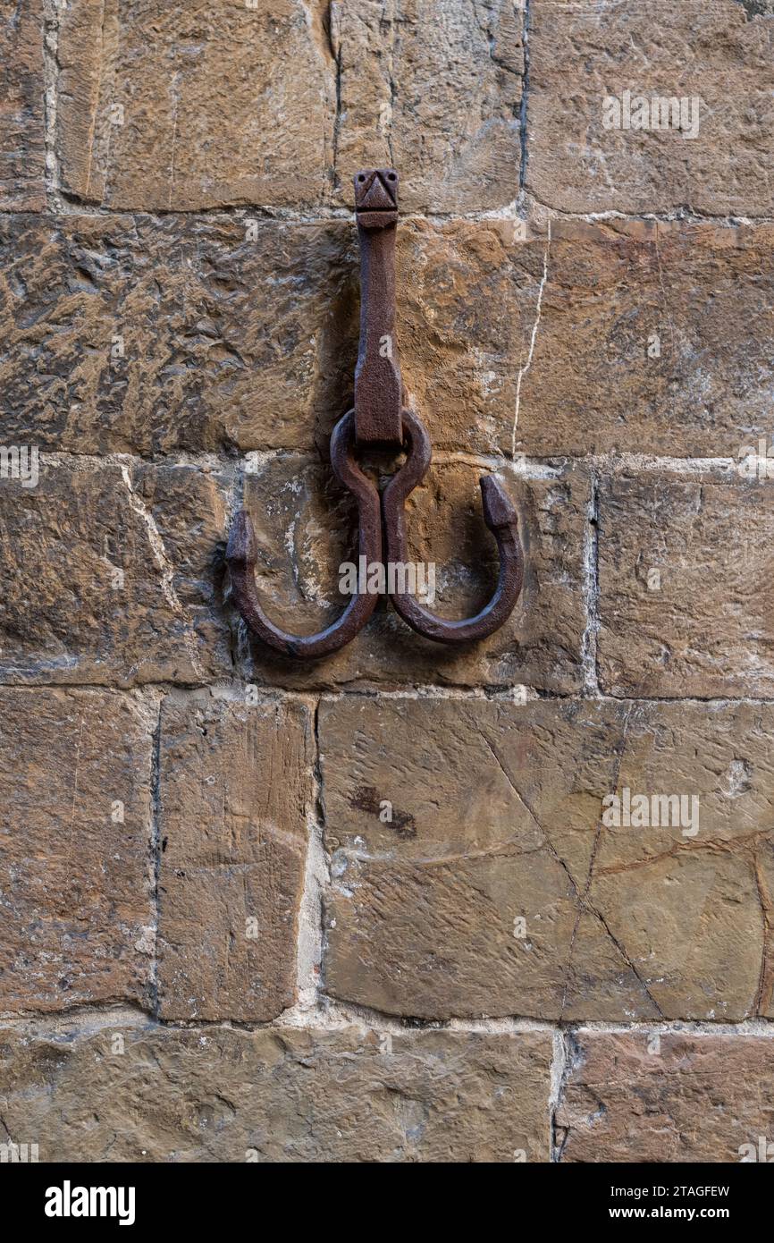 Due ganci in metallo arrugginito utilizzati per fissare porte e persiane e per agganciare cavalli sono montati all'esterno di un edificio in Italia. Foto Stock