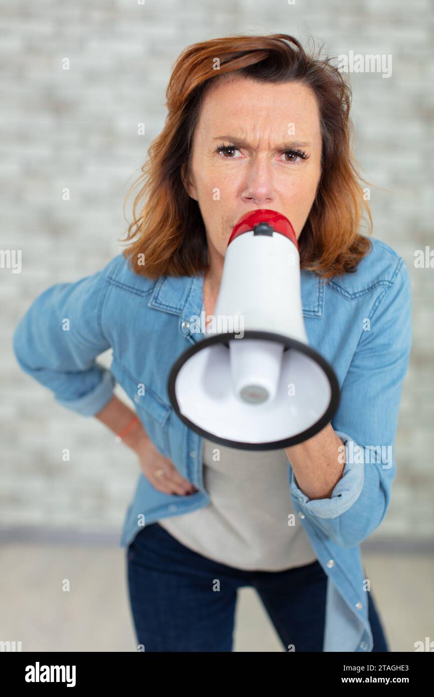 donna arrabbiata gridando nel megafono Foto Stock