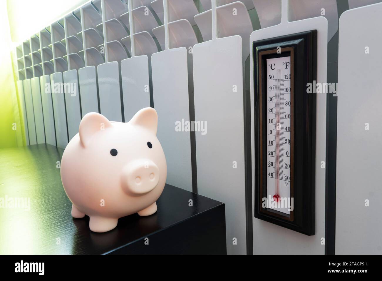 Salvadanaio con termometro sul tavolo vicino al radiatore di riscaldamento. Crisi energetica, efficienza energetica e aumento dei costi di riscaldamento in Europa Foto Stock