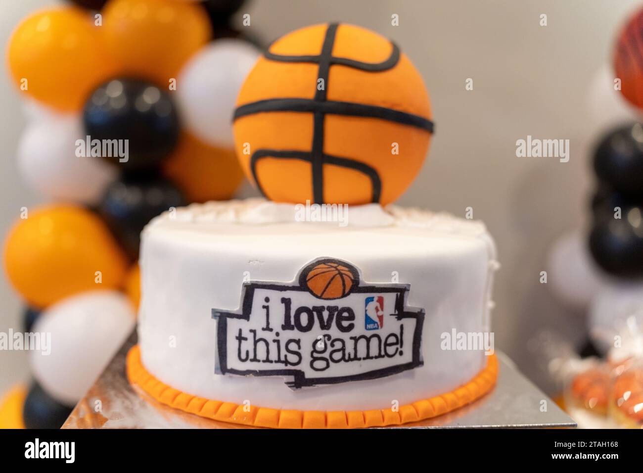 Buona torta di compleanno, amo questo gioco, il tema del basket. Logo NBA. Palloncini neri, bianchi e arancioni. Sullo sfondo. Muro bianco. Foto Stock