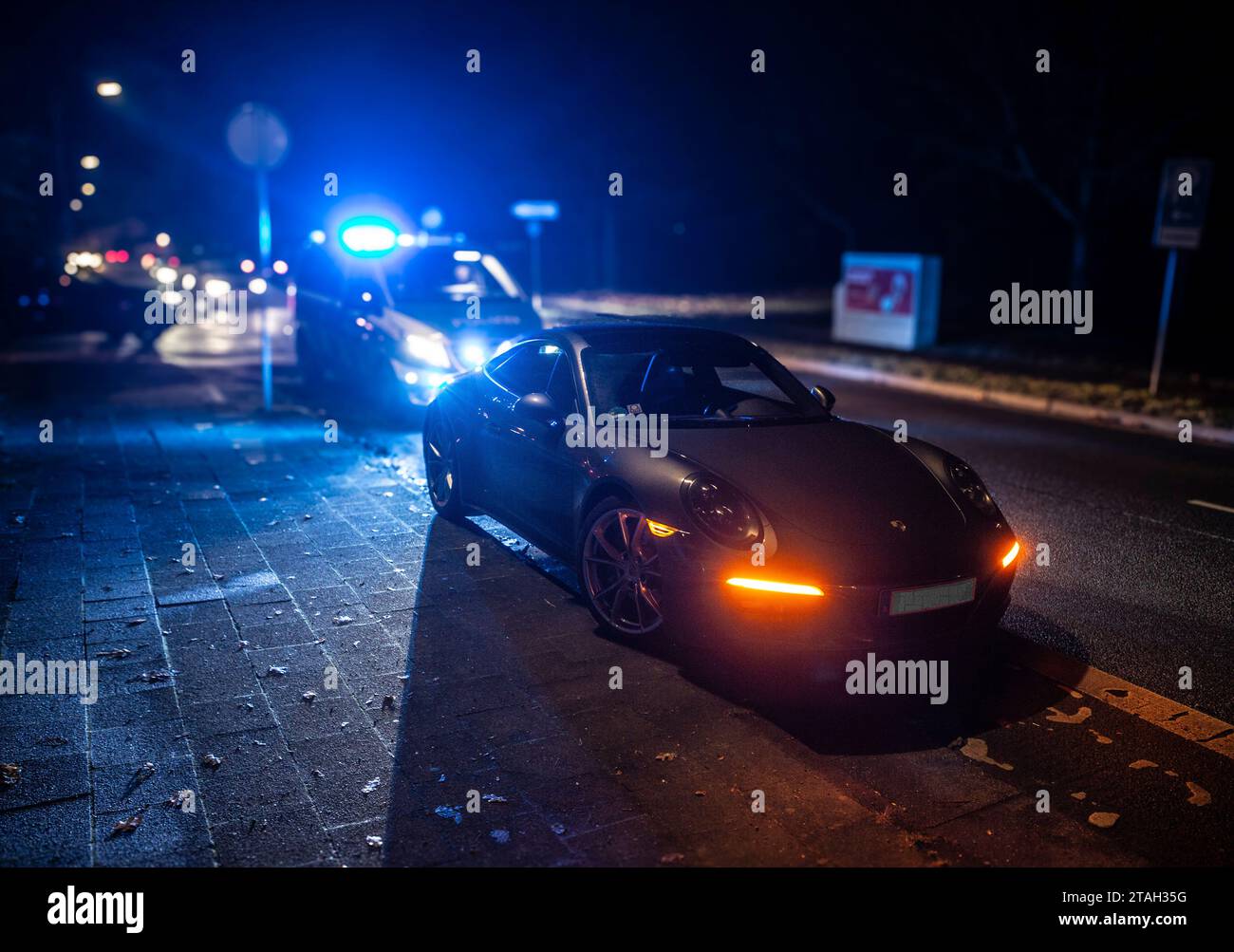 Ein Streifenwagen der Polizei mit eingeschalteten Blaulicht hinter einem Porsche Carrera 911 S4 nach einem Verkehrsunfall mit Bagatellschaden. Foto Stock