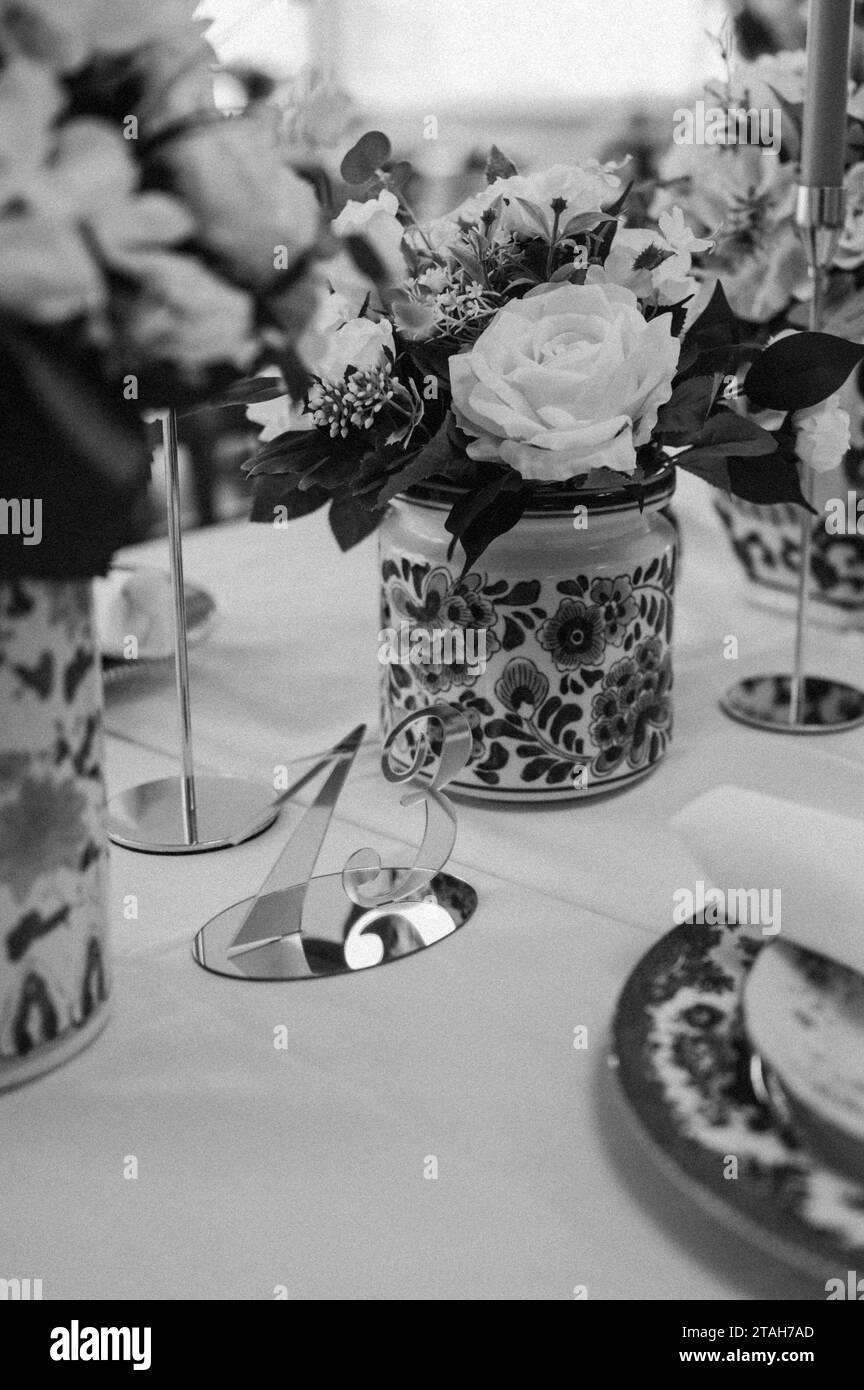 Un assortimento di fiori disposti in un vaso poggiato su un tavolo in scala di grigi Foto Stock