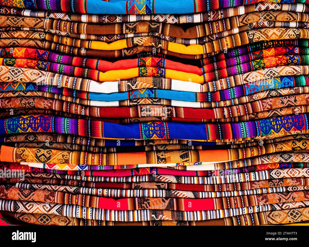 Pila di tessuti e tessuti andini multicolori nel mercato tradizionale di Pisac, Perù Foto Stock
