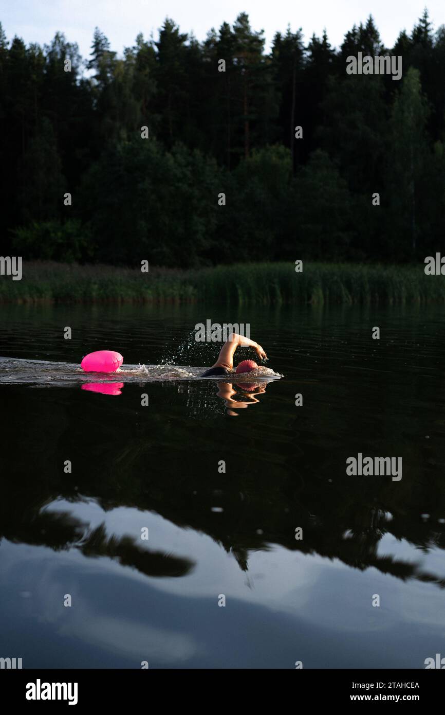Nuotatore professionista in muta nuota in mare aperto su un lago. Foto Stock