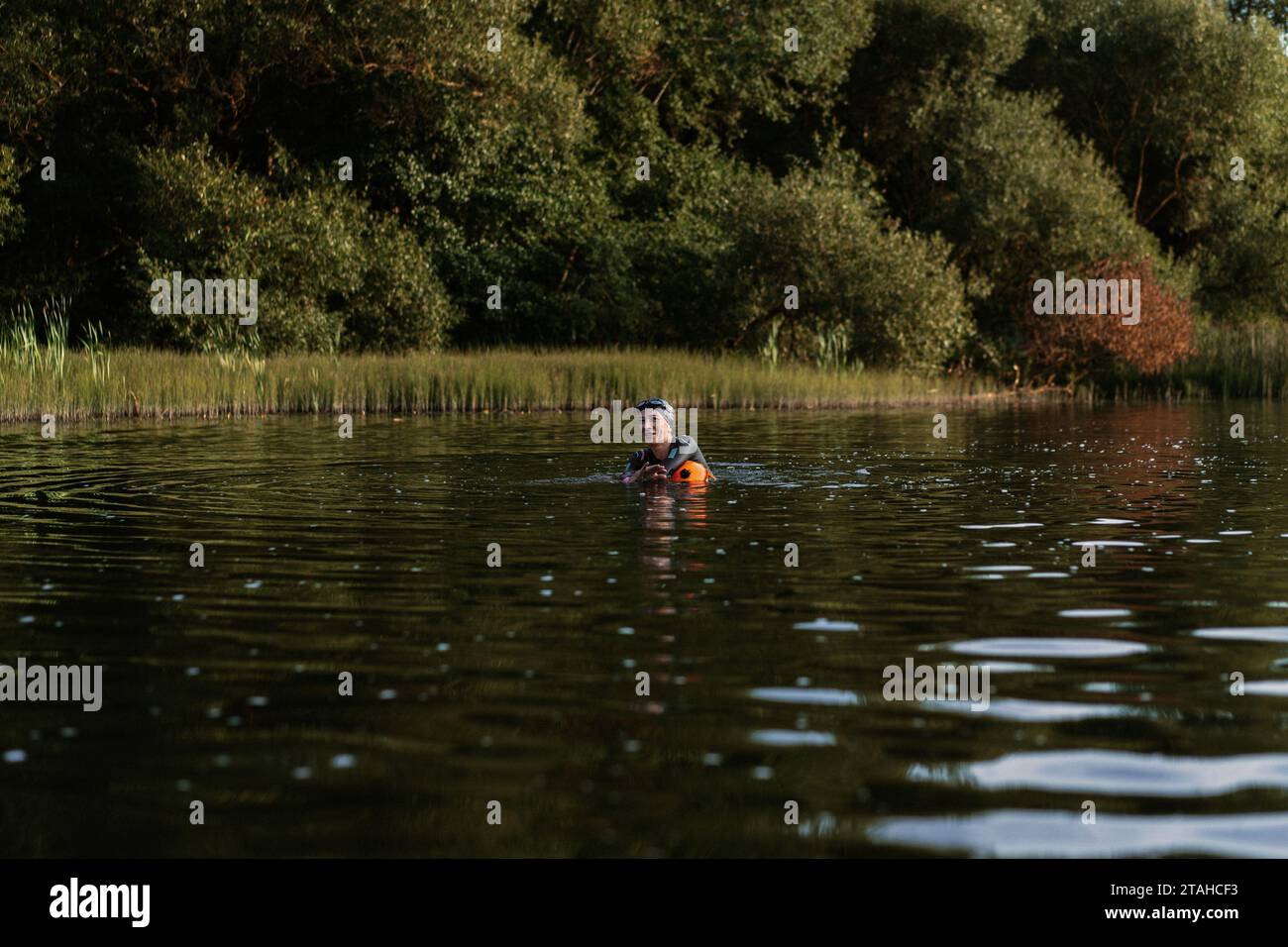 Nuotatore professionista in muta nuota in mare aperto su un lago. Foto Stock