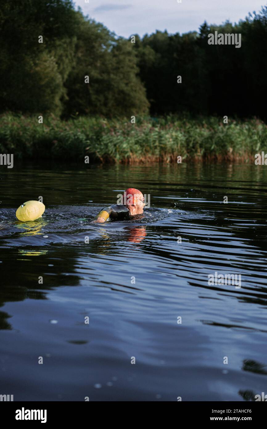 Nuotatore professionista in muta nuota in mare aperto su un lago. Foto Stock