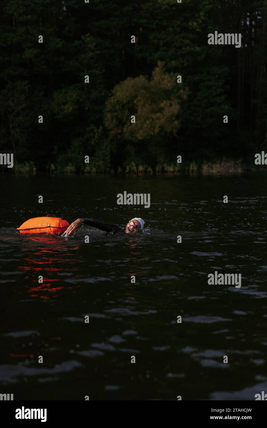 Nuotatore professionista in muta nuota in mare aperto su un lago. Foto Stock