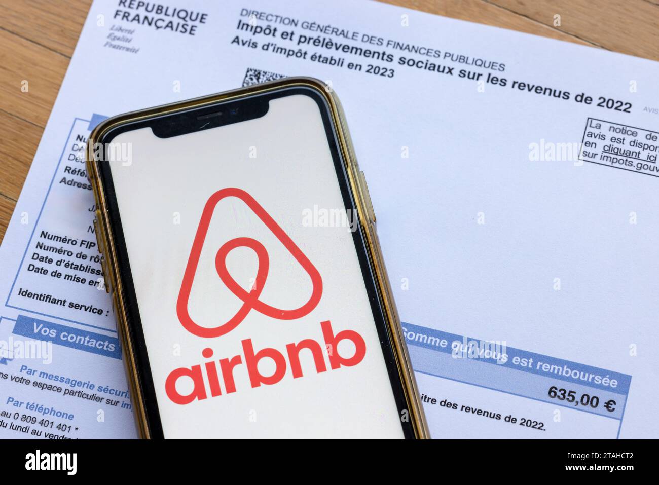 Parigi, Francia - 30 novembre 2023: Logo Airbnb su uno smartphone su una ricevuta fiscale. Il governo francese vuole tassare di più gli affitti a breve termine. Foto Stock