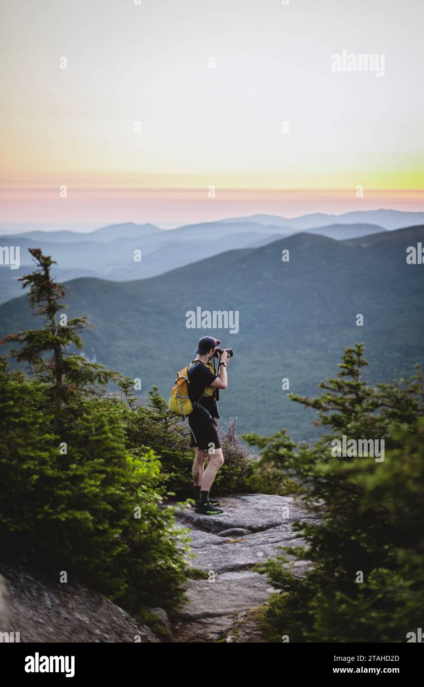 Escursionista maschile con attrezzatura da trekking e fotocamera per scattare foto della vista sulle montagne Foto Stock