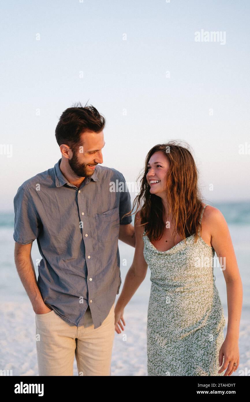 Fratello e sorella sorridono l'uno all'altro in spiaggia in vacanza Foto Stock