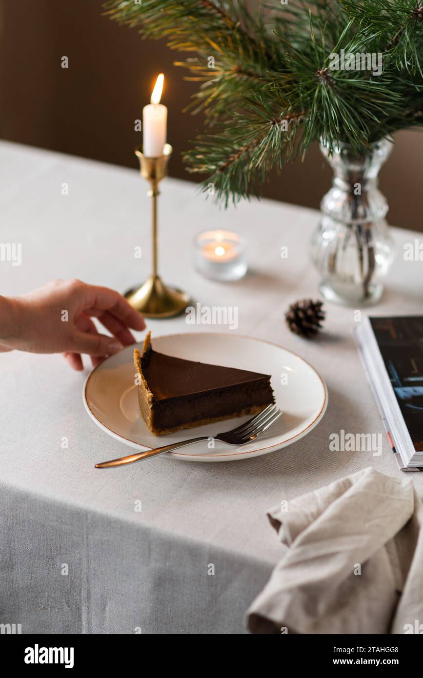 Atmosfera accogliente con rami di abete, candele e fette di torta Foto Stock