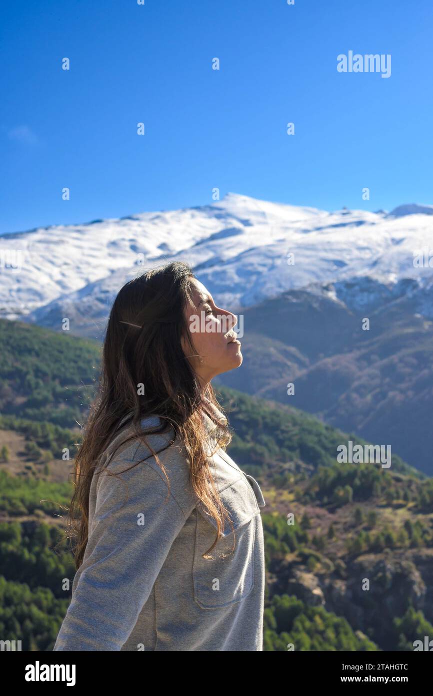 donna latina, capelli lunghi, respira aria fresca in cima alla montagna Foto Stock