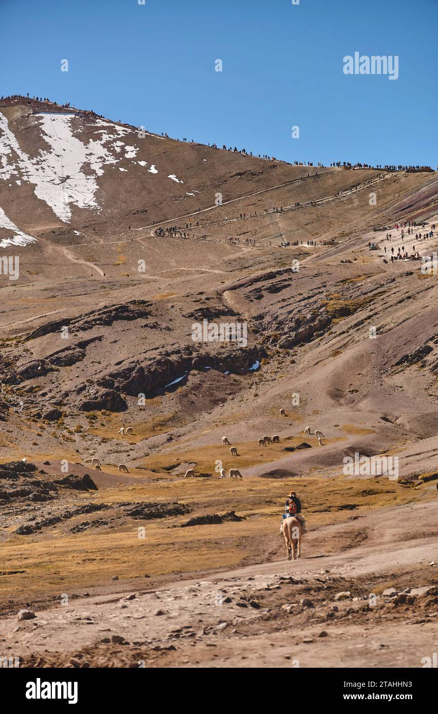 Guida nativa con turista a cavallo con abiti tradizionali durante il tour a piedi della colorata montagna Arcobaleno vicino a Cusco, in Perù Foto Stock
