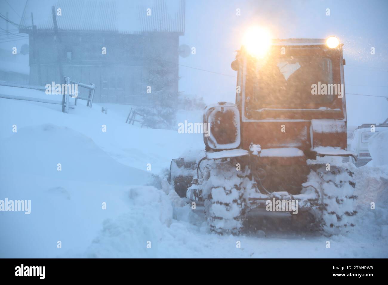 Il trattore pulisce la strada in caso di nevicate. Stagione invernale Foto Stock