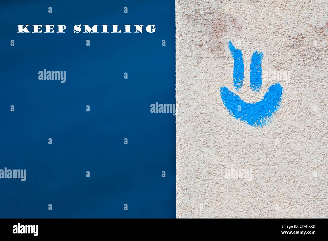 Emozione positiva e concetto sorridente. Emoji blu sull'edificio e sfondo blu. Spazio di copia negativo per il posizionamento del testo. Continua a sorridere. Foto Stock