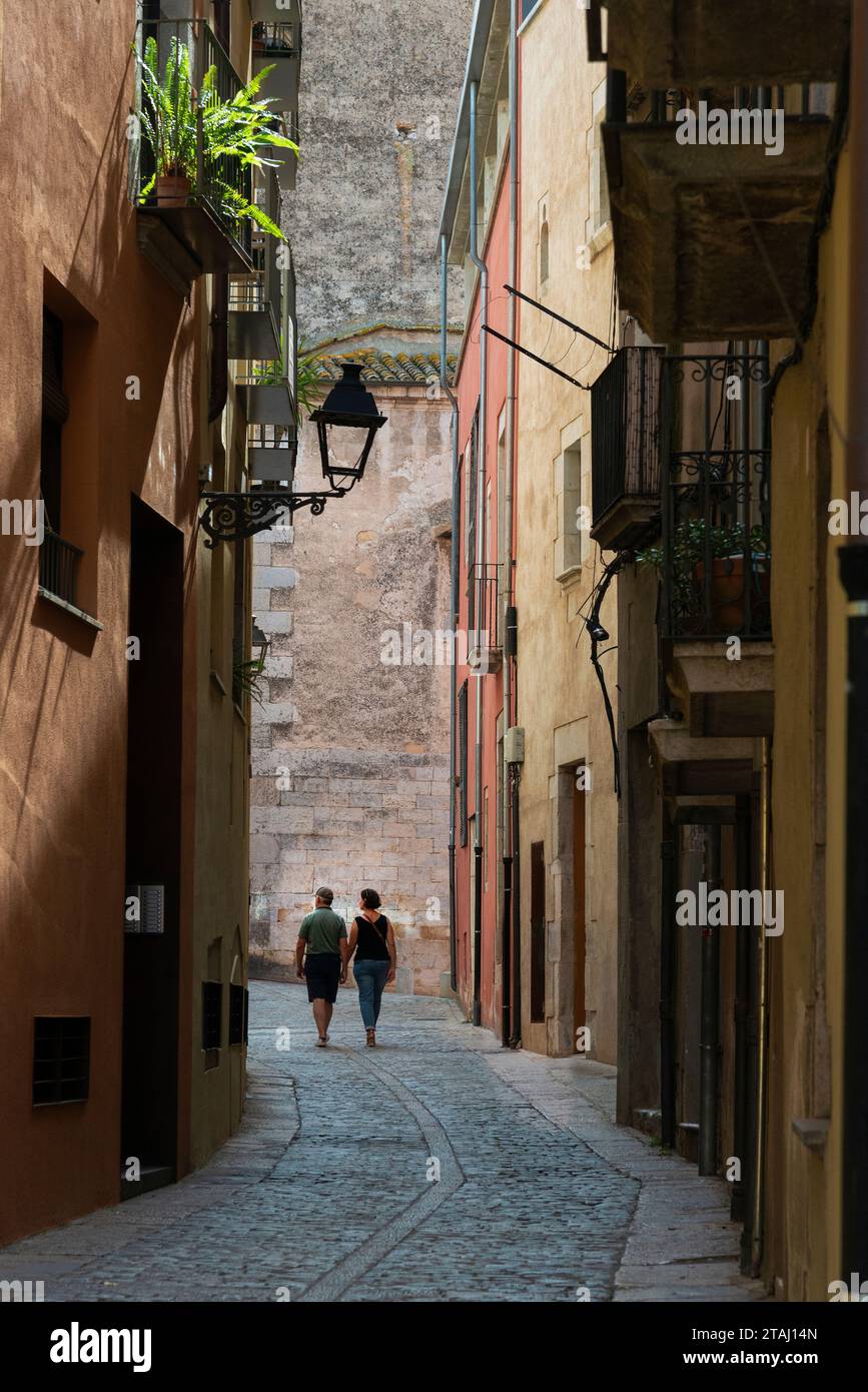 Una coppia che cammina lungo una strada pittoresca nella storica e medievale città vecchia di Girona, Catalogna, Spagna Foto Stock