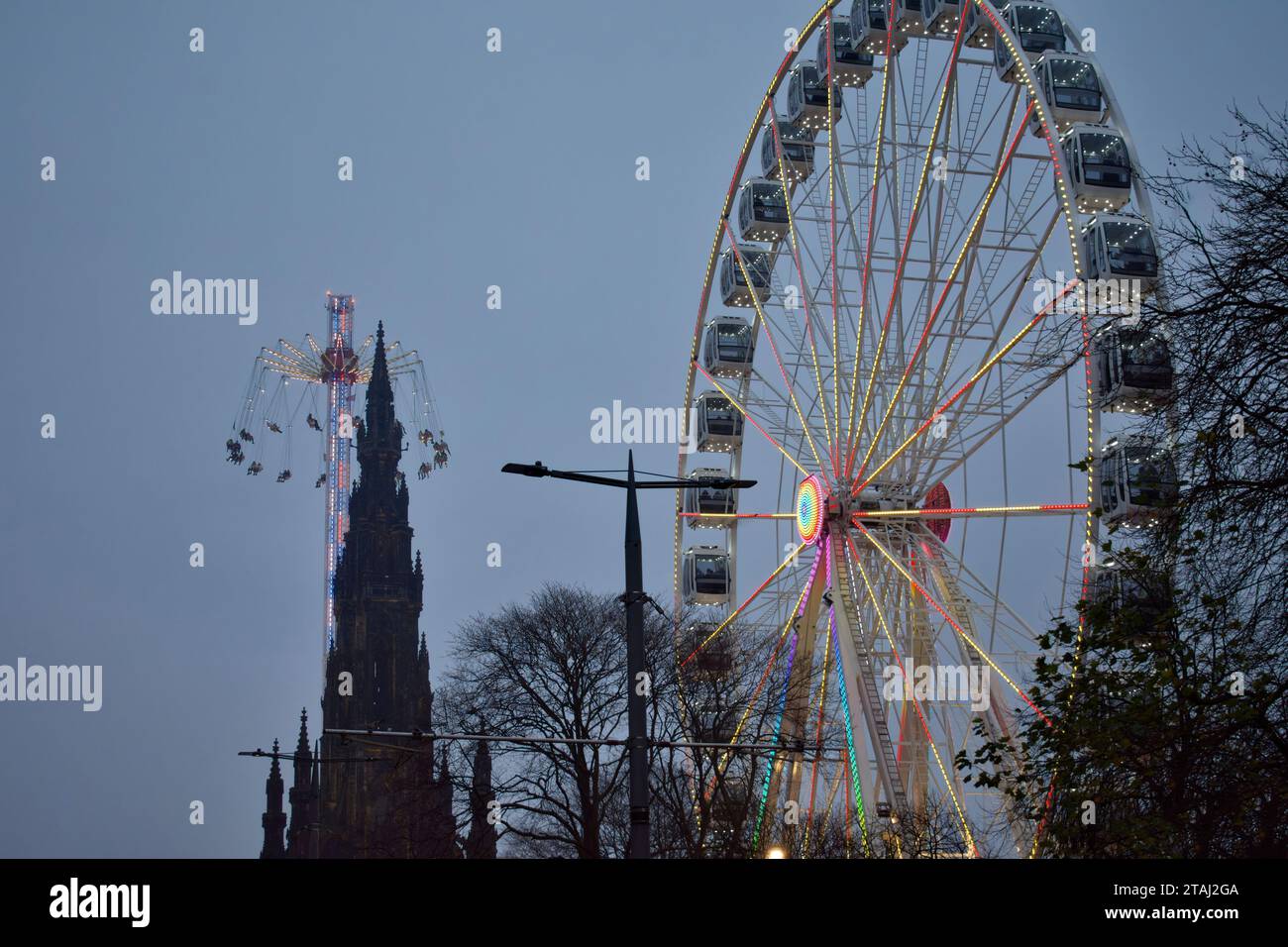 Edinburgh Scotland Christmas Fair o Market Princes Street una vista serale del colorato Big Wheel Star Flyer e del monumento Scott Foto Stock