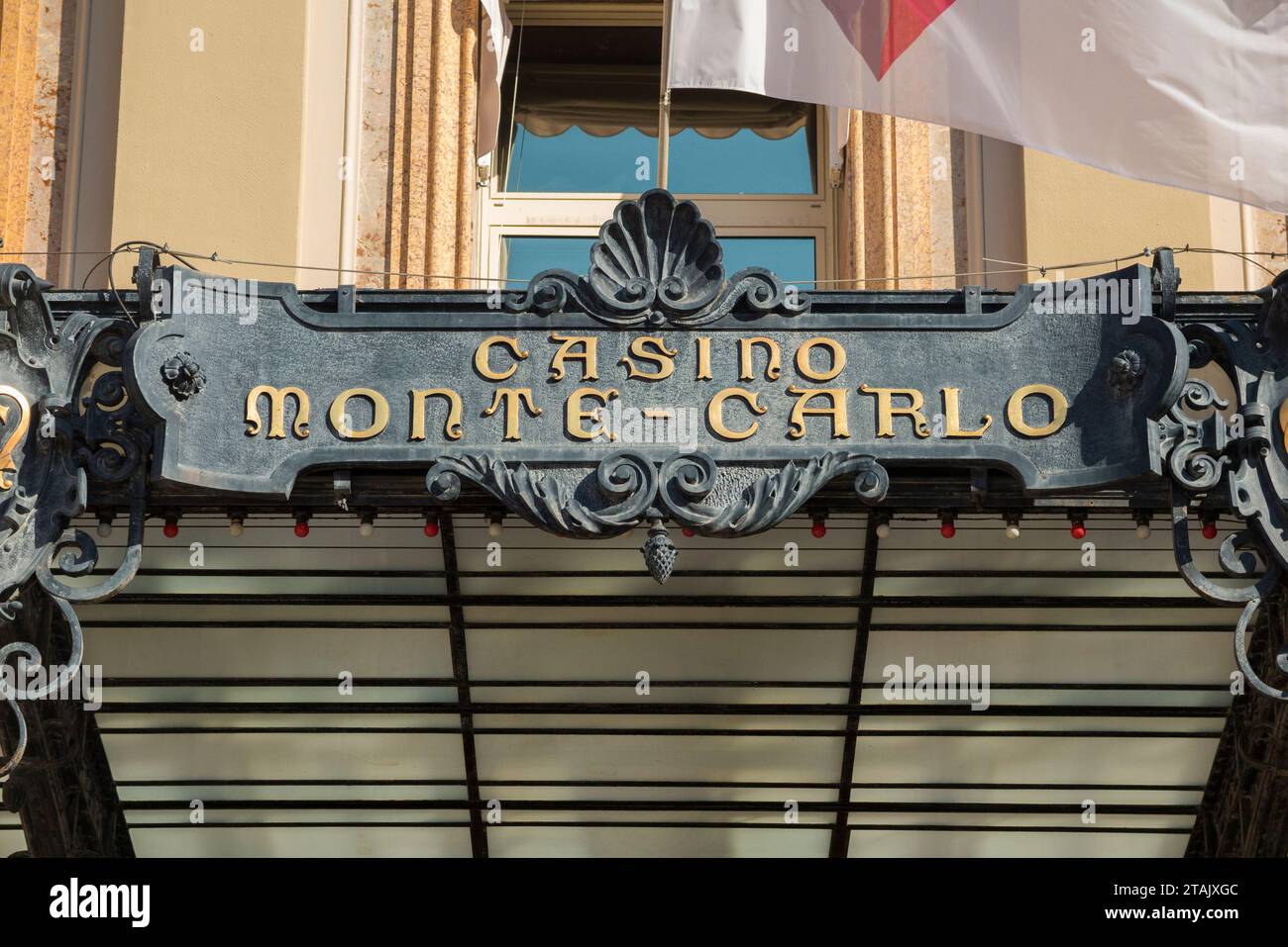 Cartello sopra l'ingresso principale esterno di Monte Carlo / Monte-Carlo Casino, Monaco. Una bandiera vola nella brezza estiva. (135) Foto Stock