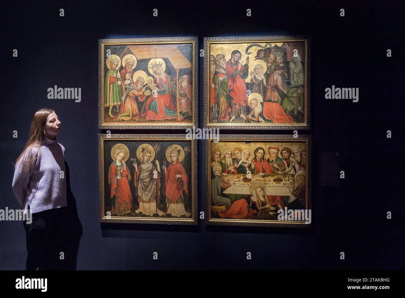 LONDRA, REGNO UNITO - 01 DICEMBRE 2023: Un membro dello staff della galleria guarda quattro pannelli della pala della Maddalena di Hildesheim (a) l'adorazione dei Magi; (b) tre santi: Maria Maddalena, Agostino e Livino; (c) l'innalzamento di Lazzaro; (d) la cena nella casa di Simone il Fariseo (stima: €500.000 - 700.000) durante una foto alla casa d'aste Sotheby's che mostra i punti salienti delle vendite della Old Masters Week a Londra, Regno Unito, il 1° dicembre 2023. Gli sconti serali della settimana Masters di dicembre si estendono tra l'inizio del XV e l'inizio del XX secolo e includono una vasta gamma di prodotti Foto Stock